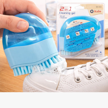 Blue shoe cleaning brush being used on a white sneaker with product packaging in the background.