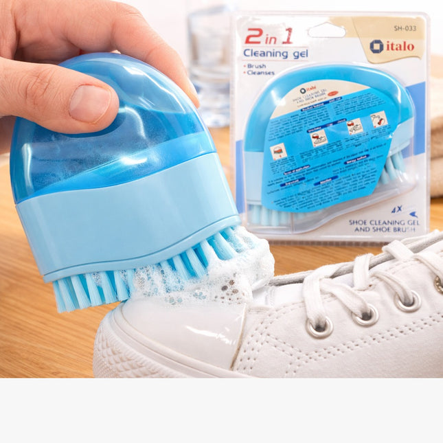 Blue shoe cleaning brush being used on a white sneaker with product packaging in the background.