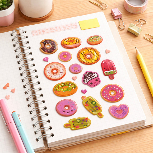 Notebook with colorful dessert-themed stickers on a wooden desk.