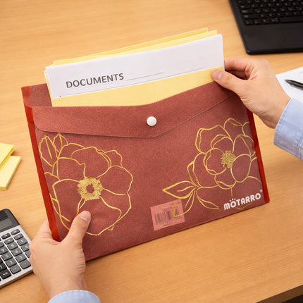 Person holding a floral-patterned document holder with 'DOCUMENTS' paper on a desk.