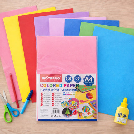 Colorful sheets of paper with a package labeled 'Motarro' on a wooden surface, surrounded by scissors and glue.