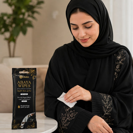 A woman in a black abaya and hijab is shown wiping her hand with a white disinfectant wipe from Halo, with the product packaging standing on a table beside her.
