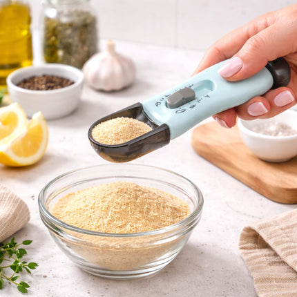 Hand using a measuring scoop to transfer flour into a glass bowl on a kitchen counter.