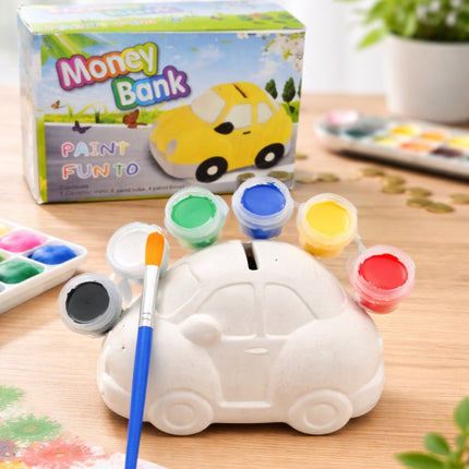 Car-shaped money bank with paint supplies on a wooden surface