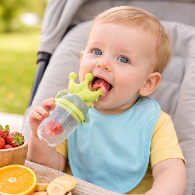 Baby eating from a fruit pouch with a bowl of strawberries and an orange in the background