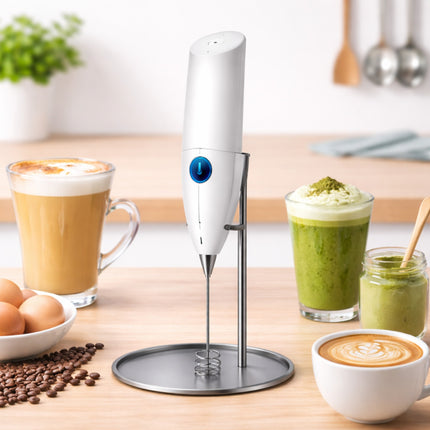 White handheld milk frother on a kitchen counter with coffee and matcha drinks.