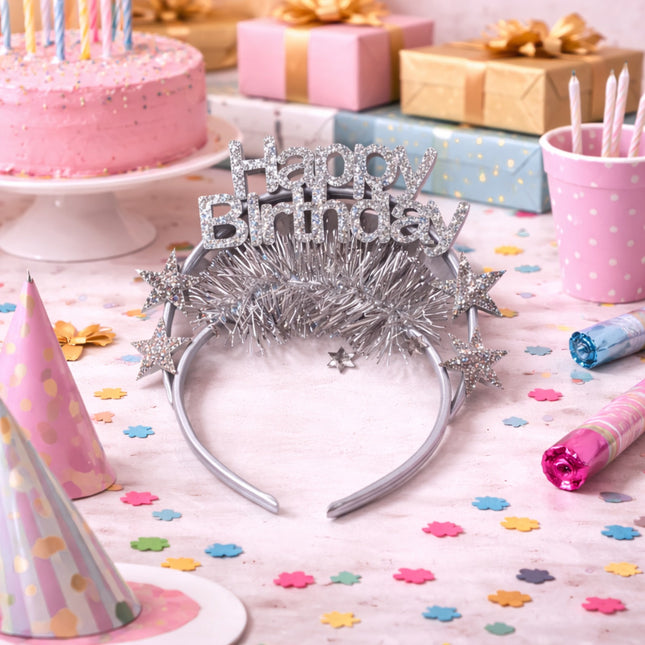 Silver 'Happy Birthday' tiara on a table with birthday cake, presents, and decorations.