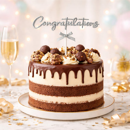 Chocolate cake with decorative elements on a white plate, surrounded by festive lights and a glass of champagne.