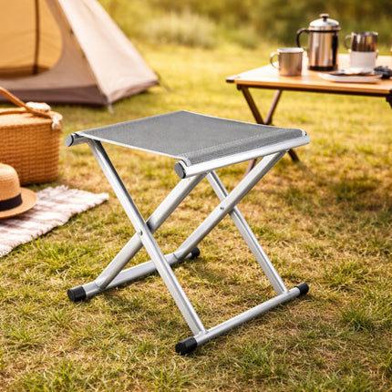 Foldable stool on grass with camping setup in the background