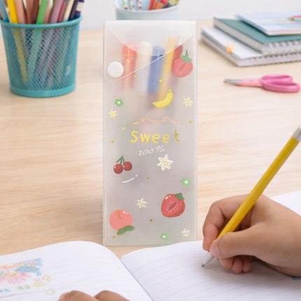 Child writing with a yellow pencil next to a clear pouch with fruit illustrations on a desk.