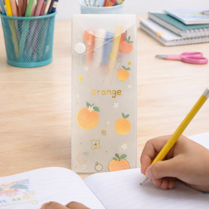 Child writing with a pencil on paper, next to a stationery holder with orange-themed design on a wooden table.