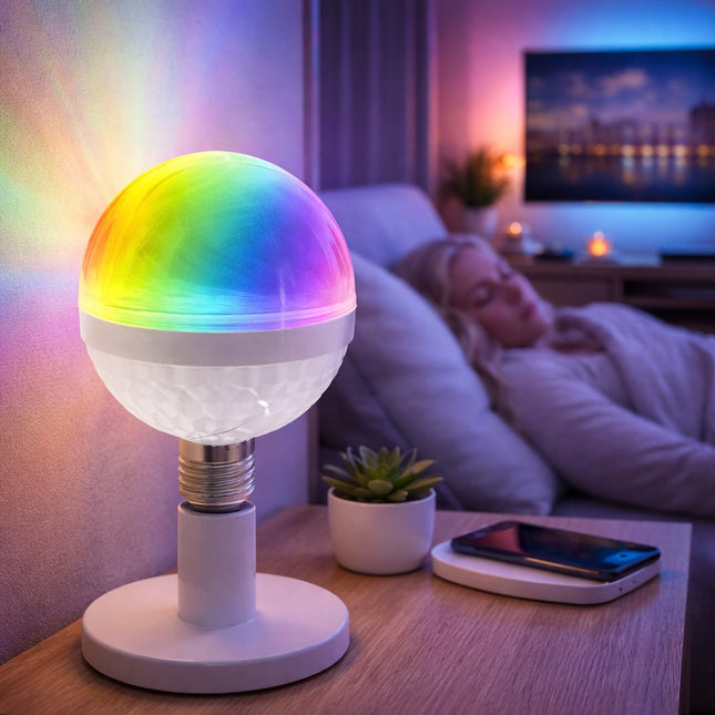 Colorful LED light bulb on a table with a person lying on a couch in the background.