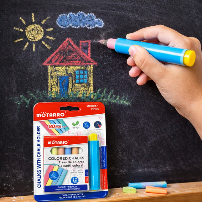 Hand holding a blue chalk with a drawing of a house and sun on a blackboard, Motarro colored chalks packaging in the foreground.