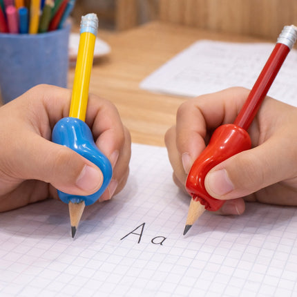 Two hands holding blue and red pencil grips on writing instruments, with a focus on letter 'A' on paper.