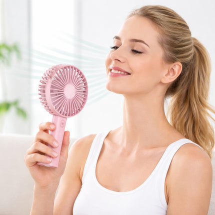 Woman holding a pink handheld fan in a bright indoor setting
