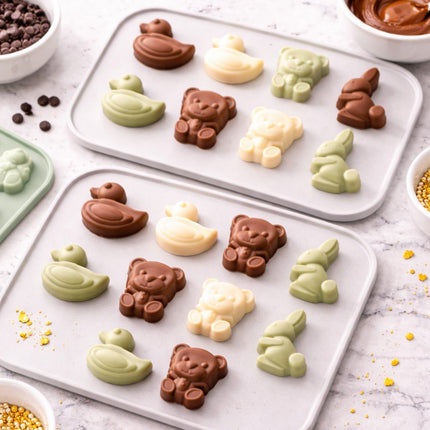 Assorted animal-shaped chocolates on a white tray with ingredients around.