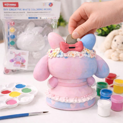 Pink and blue character piggy bank with a hand placing a coin into it, surrounded by art supplies.