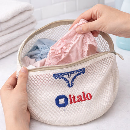 Hands holding a mesh laundry bag with 'italo' branding, containing pink underwear.