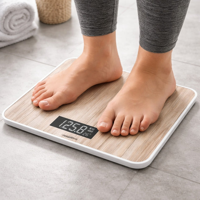 Person standing on a digital bathroom scale with wooden finish on a tiled floor.