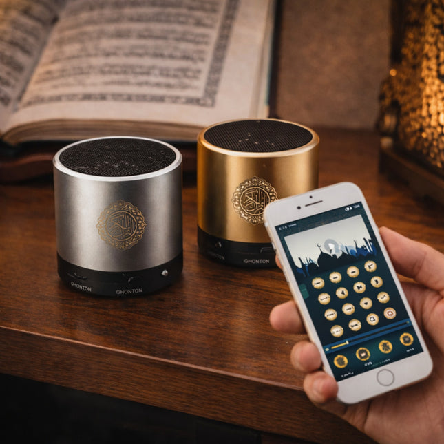Two cylindrical speakers on a wooden surface with a smartphone displaying a music app.