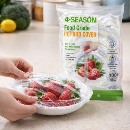 Hand using 4-Seasons food grade PE food cover to wrap strawberries on a kitchen counter.