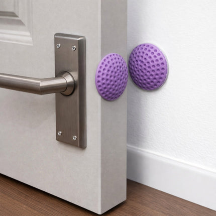 Purple door stopper attached to a door handle on a white door.