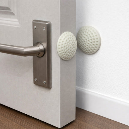 Close-up of a door handle with golf ball-shaped doorknobs on a white door.