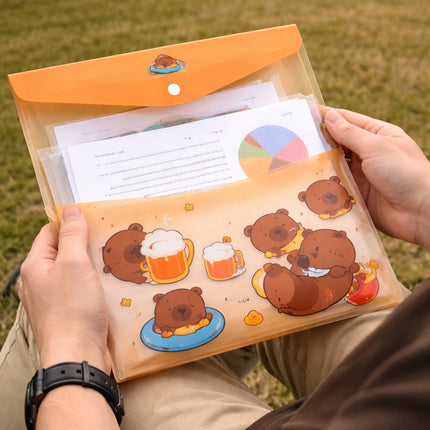Person holding a folder with cartoon bear illustrations on a grassy background