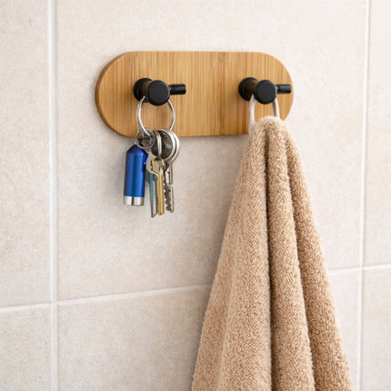 Wooden wall hook with keys and a towel on a tiled wall