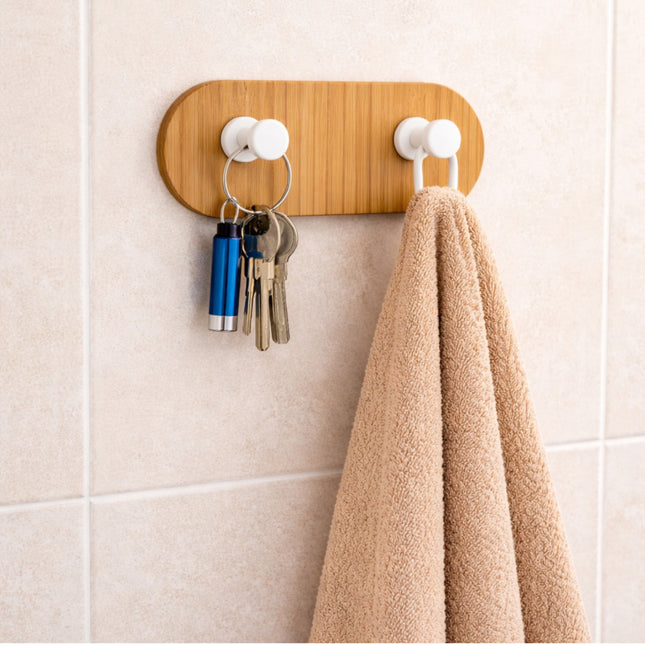 Wooden wall hook with keys and a towel on a tiled wall