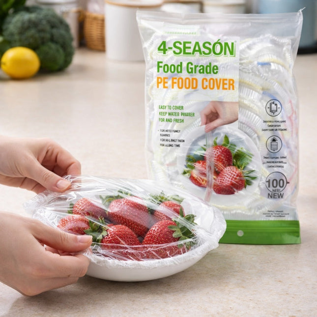 Hand using 4-Seasons food grade PE food cover to wrap strawberries on a kitchen counter.