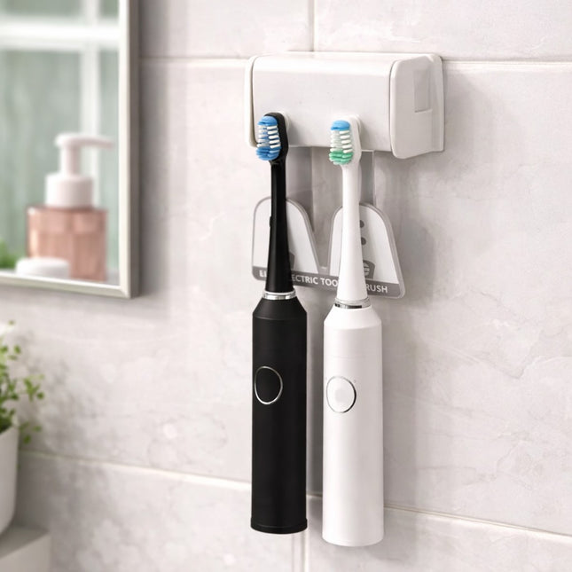 Two electric toothbrushes, one black and one white, mounted on a wall-mounted holder in a bathroom.
