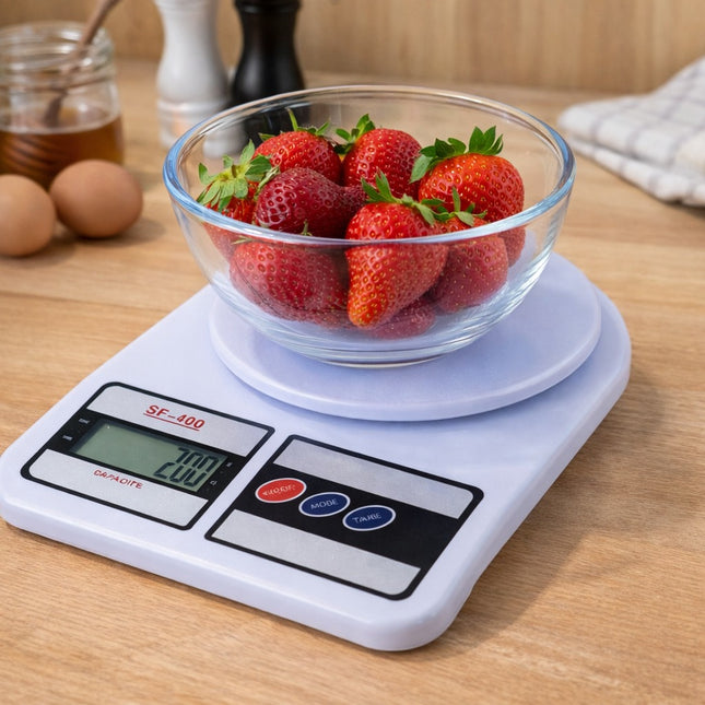 Digital kitchen scale with a bowl of strawberries on a wooden surface