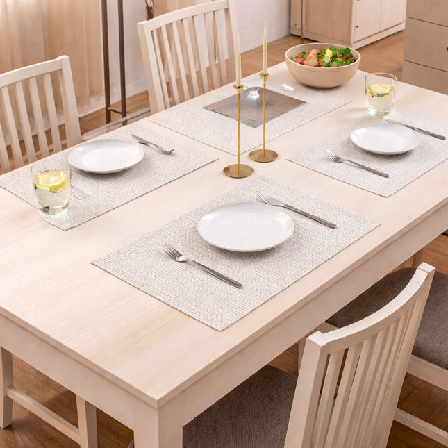 Dining table set with plates, glasses, and silverware in a kitchen.