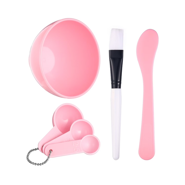 Set of pink beauty tools including a bowl, brush, and applicators on a white background