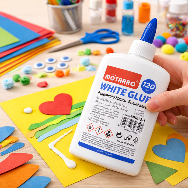 Mоторро white glue bottle held by a hand with craft materials on a table