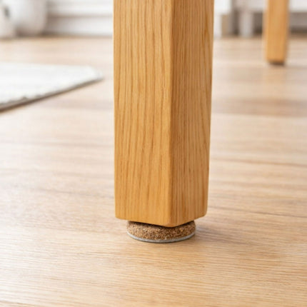 Wooden leg of a piece of furniture with a cork foot on a wooden floor.