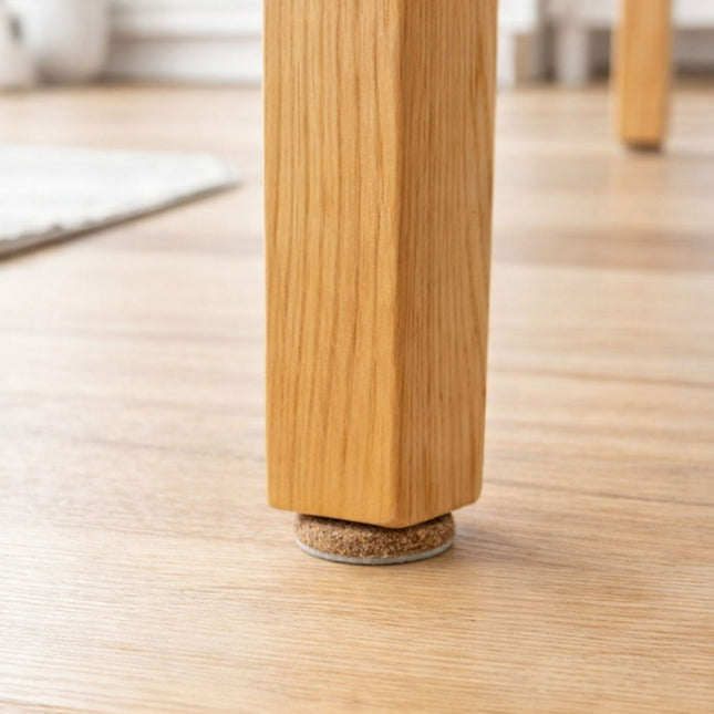 Wooden leg of a piece of furniture with a cork foot on a wooden floor.