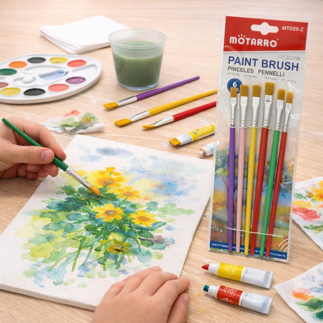 Person painting a sunflower with watercolors on a wooden table, surrounded by art supplies including a paintbrush set.
