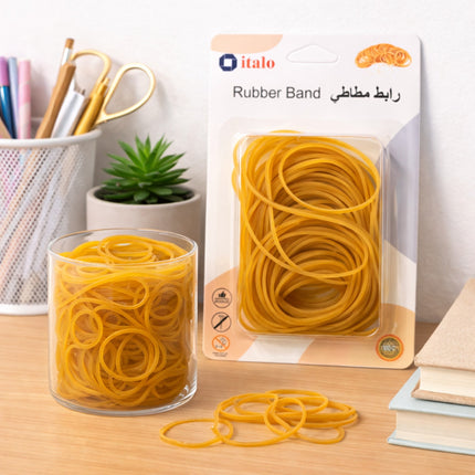 Yellow rubber bands in a glass container and packaging on a desk with stationery items.