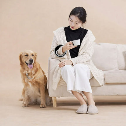 Woman sitting on a couch with a dog next to her, holding a cup.