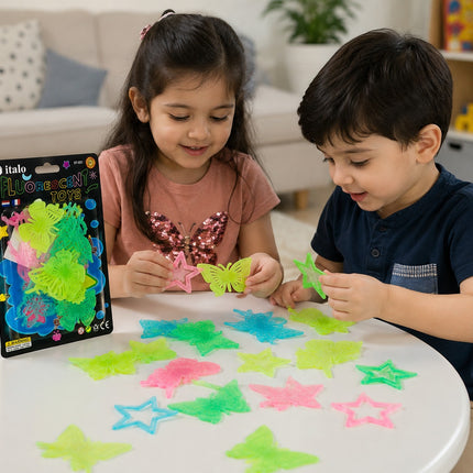 Two children sitting at a white table playing with colorful translucent star-shaped and butterfly-shaped stickers, with the Italo brand packaging visible on the left.
