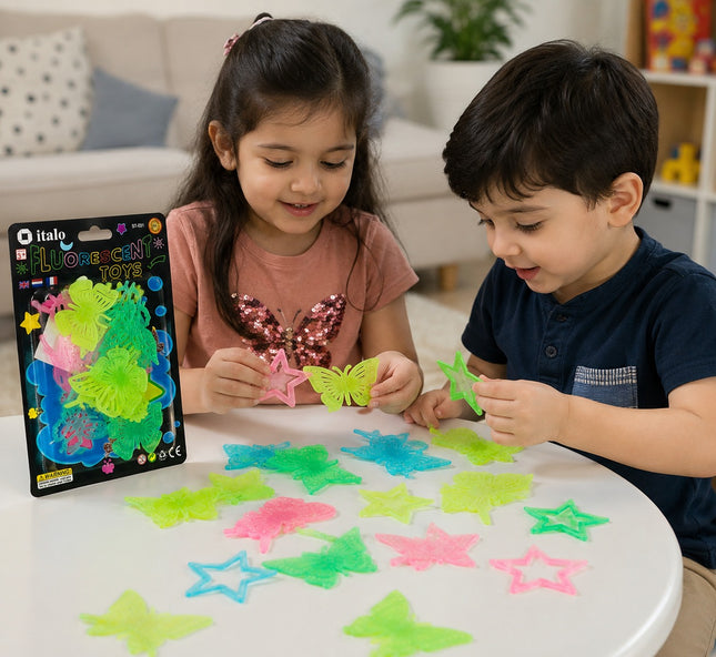 Two children sitting at a white table playing with colorful translucent star-shaped and butterfly-shaped stickers, with the Italo brand packaging visible on the left.