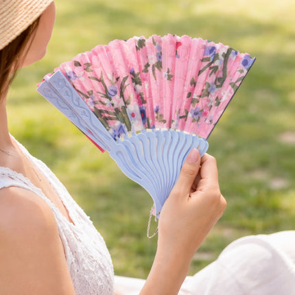 Person holding a floral-patterned hand fan outdoors