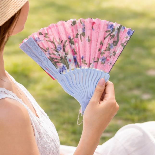 Person holding a floral-patterned hand fan outdoors