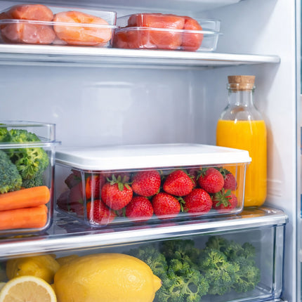 Open refrigerator with various fruits, vegetables, and a bottle of orange juice.