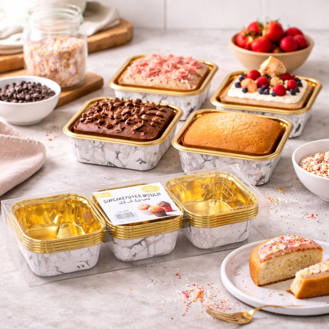 Assorted small cakes in marble-patterned containers on a light surface with strawberries and chocolate chips.