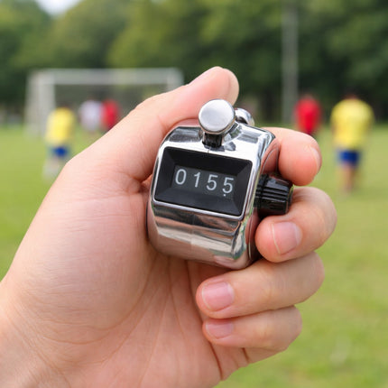 Hand holding a digital stop watch with a sports field in the background