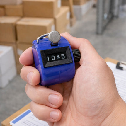 Hand holding a blue counter with numbers 1045, blurred boxes in the background