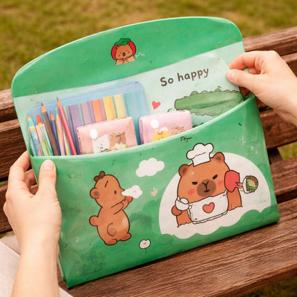Green pouch with cartoon bear design filled with stationery items on a wooden surface.